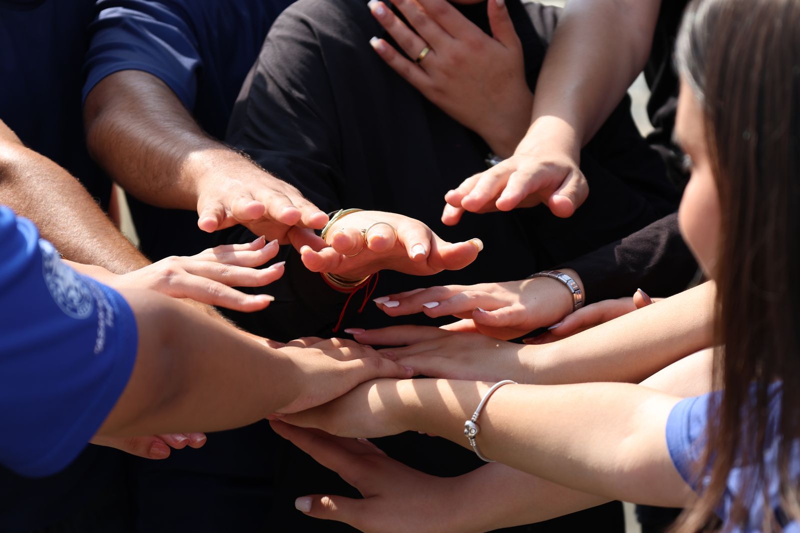 Many hands of different skin tones joined together in a circle