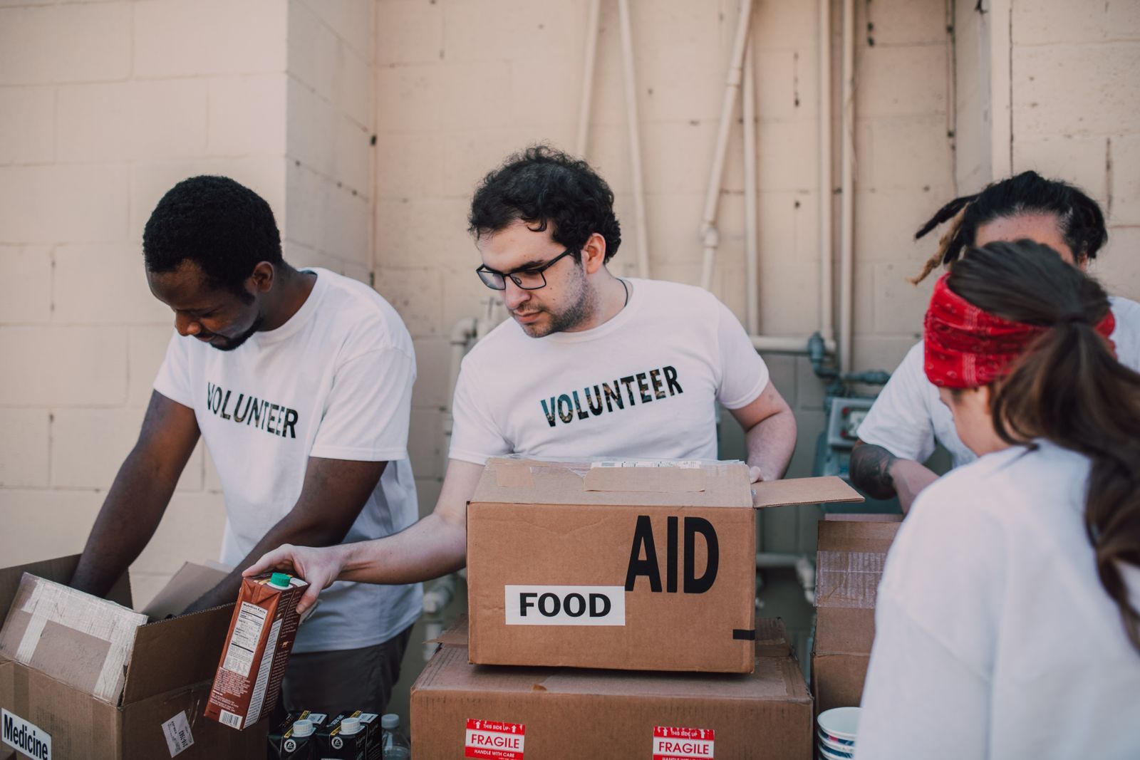 Volunteers in white T-shirts packing food into donation boxes